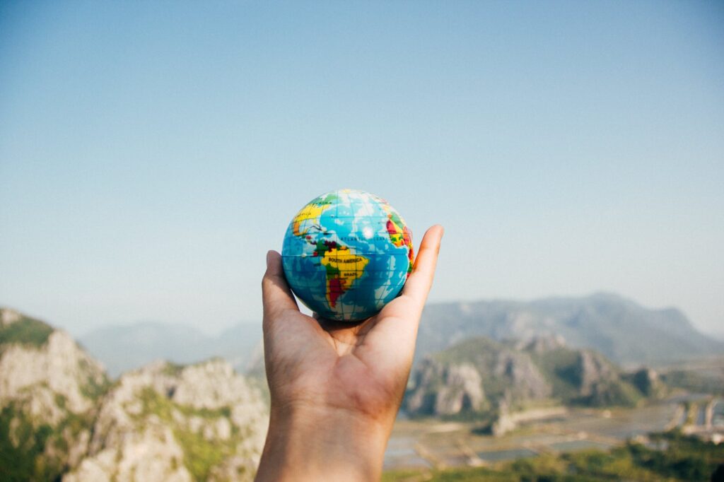 person holding world globe facing mountain. International Mother Earth Day nonfiction books
