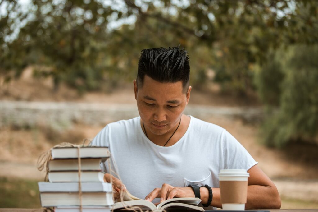 man in white t shirt reading book. Best books in May