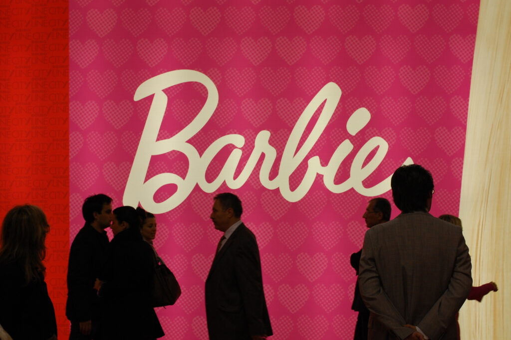 Barbie feminist books. Shadow of men in front of Barbie pink sign