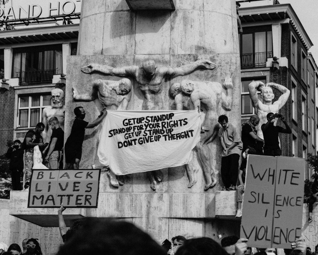 people standing near monument with placards as we look at whether BLM protests can truly work in a neoliberal society