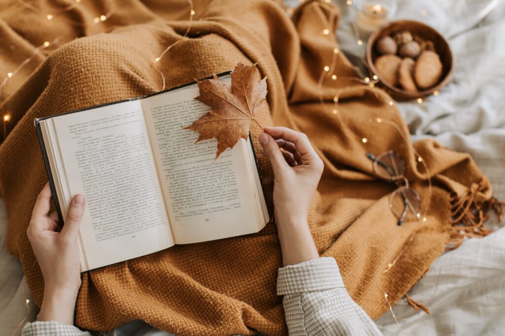 person reading a book while holding a maple leaf. Best books in September